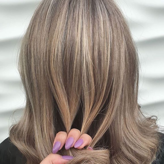 Hinterkopf einer Frau mit blondem, gewelltem Haar und Strähnen, kreiert mit Wella Professionals.
