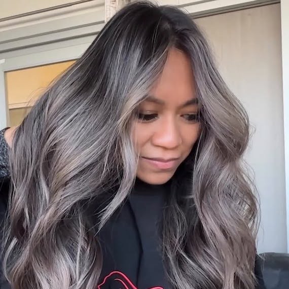 Model with long, dark hair featuring silver on the lengths and a deep root shadow.