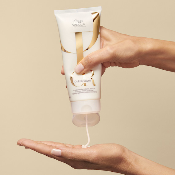 Der Oil Reflections Conditioner wird in eine Hand gedrückt.