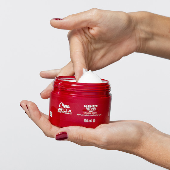 Model scoops the ULTIMATE REPAIR Mask out of the jar.