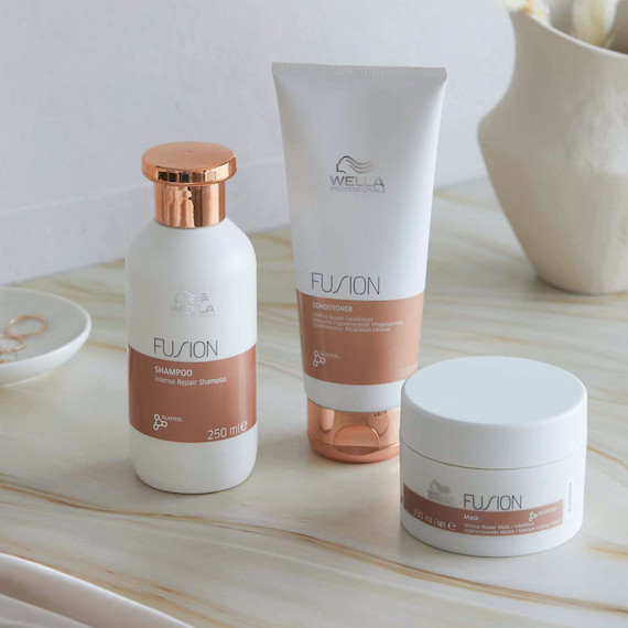 Das Fusion Shampoo, der Fusion Conditioner und die Fusion Mask stehen auf einer Marmoroberfläche.