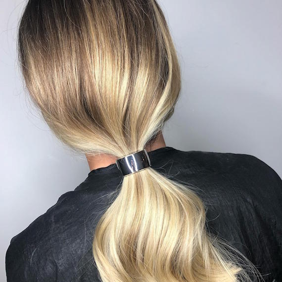 Photo of woman with blonde hair styled in a low ponytail, created using Wella Professionals.