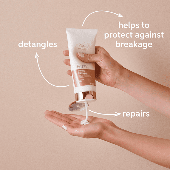 Ein Model drückt den Fusion Intense Repair Conditioner auf die Handfläche.