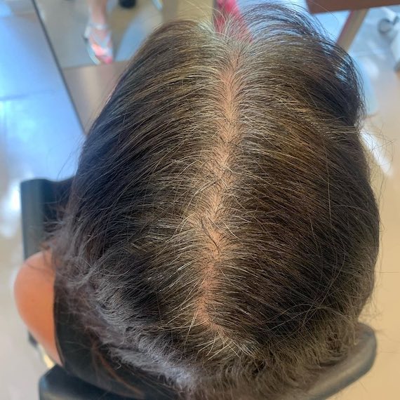 Close-up of model’s gray roots on dark brown hair.