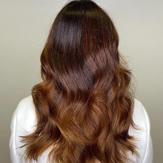 Model’s long, brown hair appearing glossy with gray roots covered by Koleston Perfect.