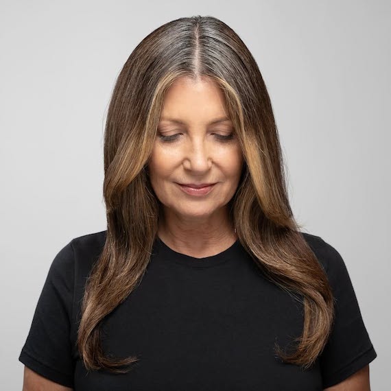 Model with long, dark brown hair featuring gray at the roots.
