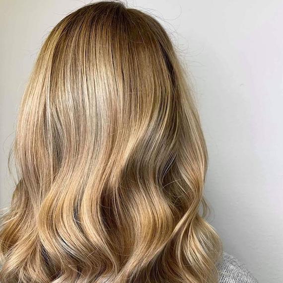 Frau mit honigblonden Babylights, kreiert mit Wella Professionals.