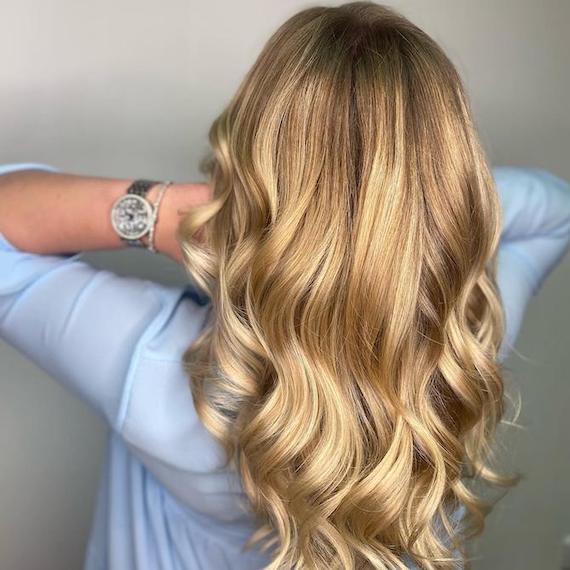 Frau mit honigblondem Haar und einer Ansatzschattierung, kreiert mit Wella Professionals.