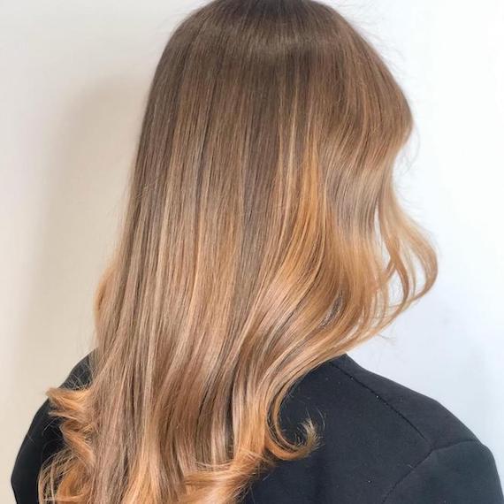 A person stood facing a white wall. They have long, light honey blonde sombre hair