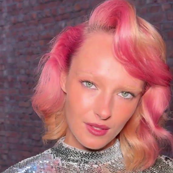 Model with bob haircut featuring peach and hot pink highlights.
