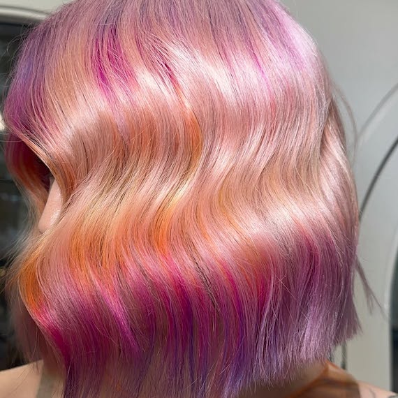 Model with a platinum blonde bob featuring hot pink, orange and violet sections.
