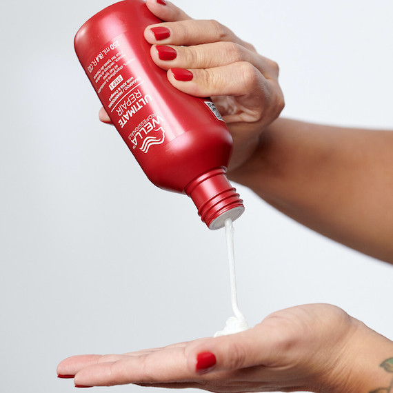 Ultimate Repair Shampoo is poured into model’s hand.
