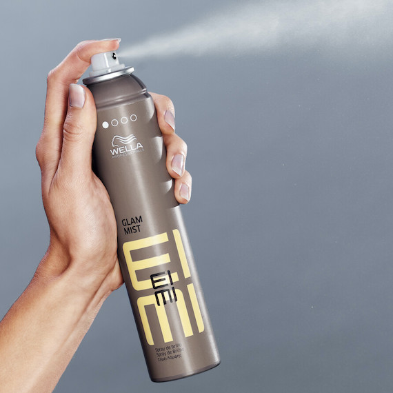 Hand holding a bottle of EIMI Glam Mist.