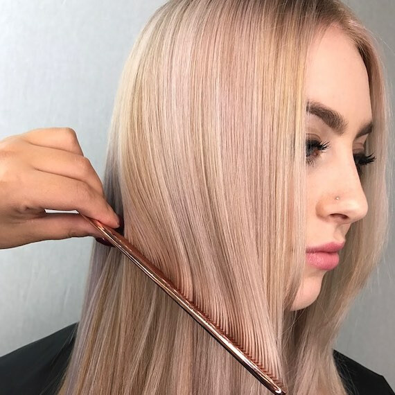 Side profile of woman having her blonde hair combed.