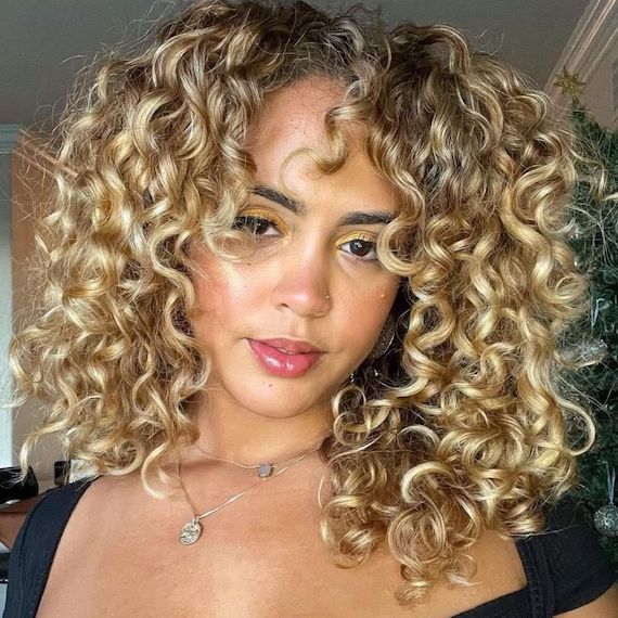 Model with golden blonde, curly hair faces camera.