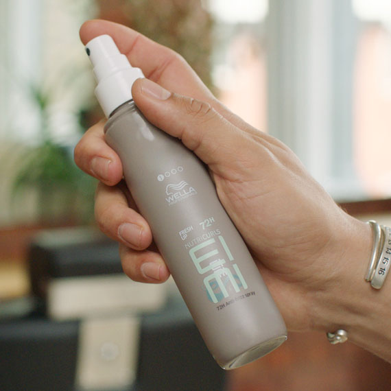 Hand holds a bottle of EIMI Fresh Up spray.