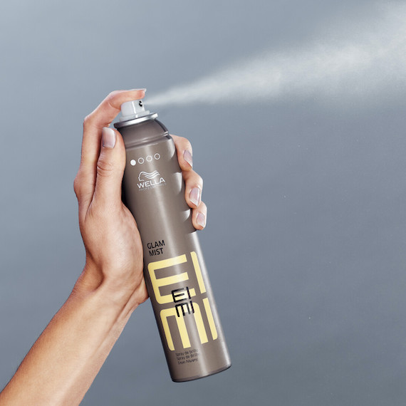 Hand holds up a bottle of EIMI Glam Mist.