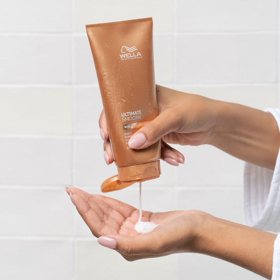 Model pours ULTIMATE SMOOTH Conditioner into palm of hand.