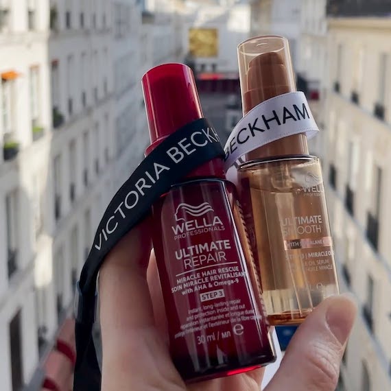 Lanyard strap that reads ‘VICTORIA BECKHAM’ is draped over bottles of ULTIMATE REPAIR and ULTIMATE SMOOTH.