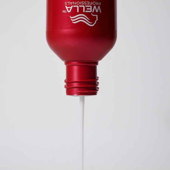 Upside down bottle of Ultimate Repair Shampoo with product being poured out.