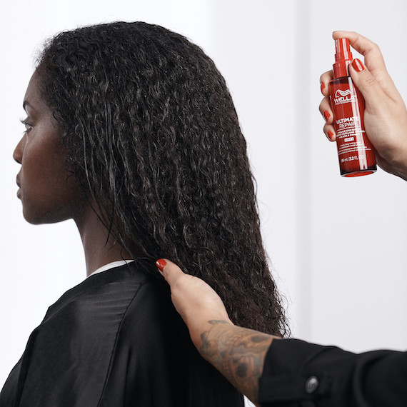 Ultimate Repair Miracle Hair Rescue is misted through model’s dark, curly hair.