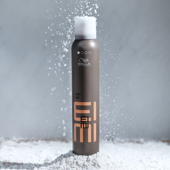 Eine Dose EIMI Dry Me Trockenshampoo auf grauem Hintergrund.