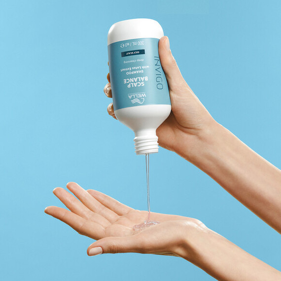 Das Model gießt das INVIGO Scalp Balance Shampoo in die Handfläche.
