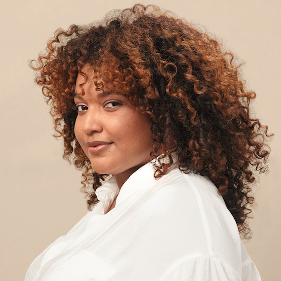 Woman with long, curly, brown hair and caramel highlights created by Wella Professionals.