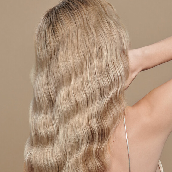 Back of model’s head. They have long, blonde, wavy hair that’s been colored using Koleston Perfect by Wella Professionals