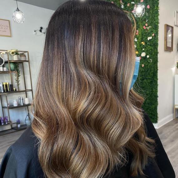 Hinterkopf einer Frau mit brünettem Haar und karamellfarbenen Strähnchen, kreiert mit Wella Professionals.