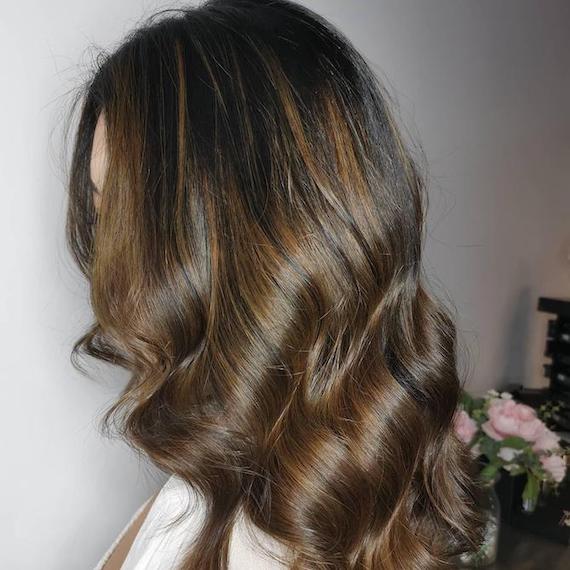 Seitenprofil einer Frau mit brünettem Haar und schokobraunen Strähnchen, kreiert mit Wella Professionals.