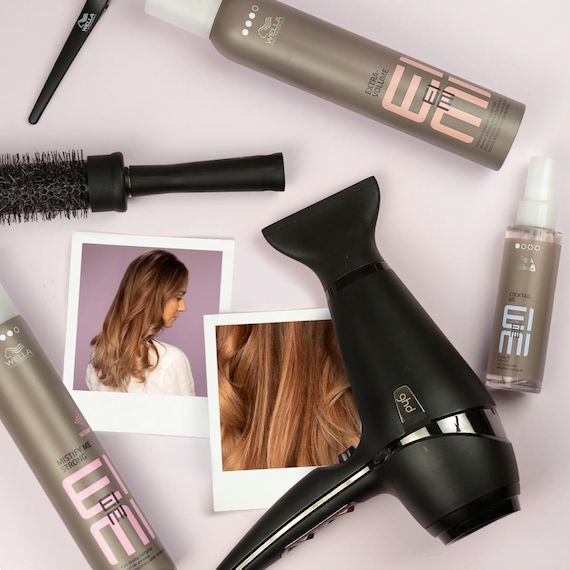 Flat lay of Wella Professionals EIMI products, hairbrush and hairdryer