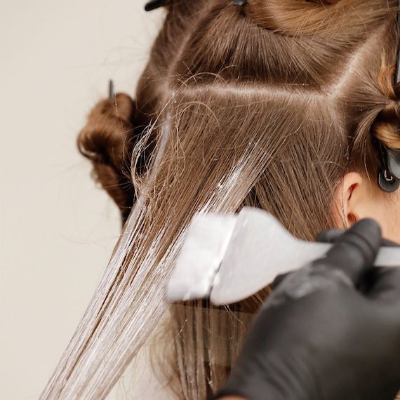 Close-up of woman with brown hair having highlights applied.