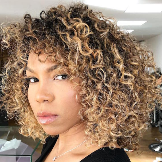 Photo of woman with curly hair and blonde highlights, created using Wella Professionals.