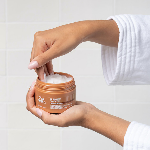 Model’s hand reaches into a jar of ULTIMATE SMOOTH Mask.
