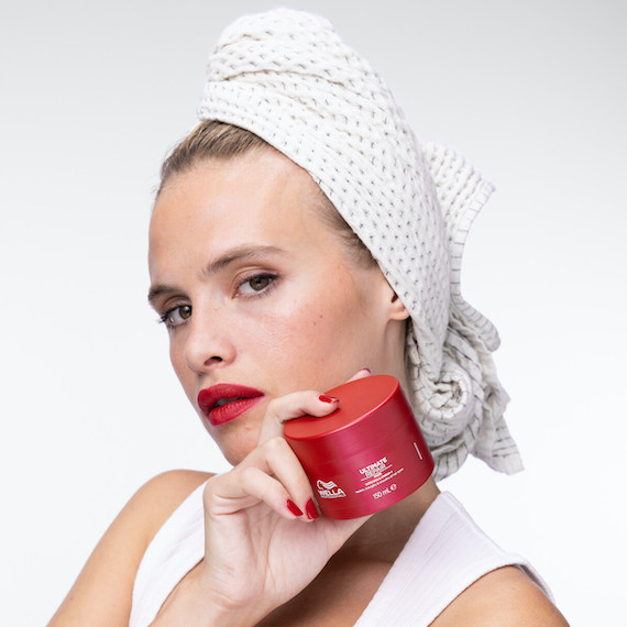 Model with hair wrapped in towel holds up ULTIMATE REPAIR Mask.