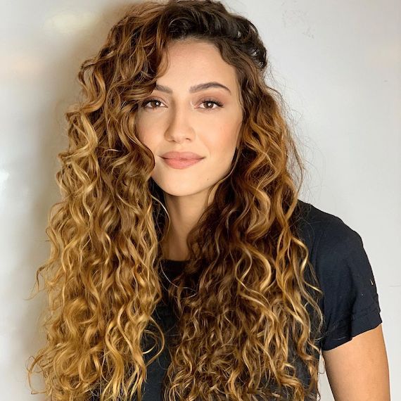 Woman smiling at the camera with long, curly, medium blonde hair.