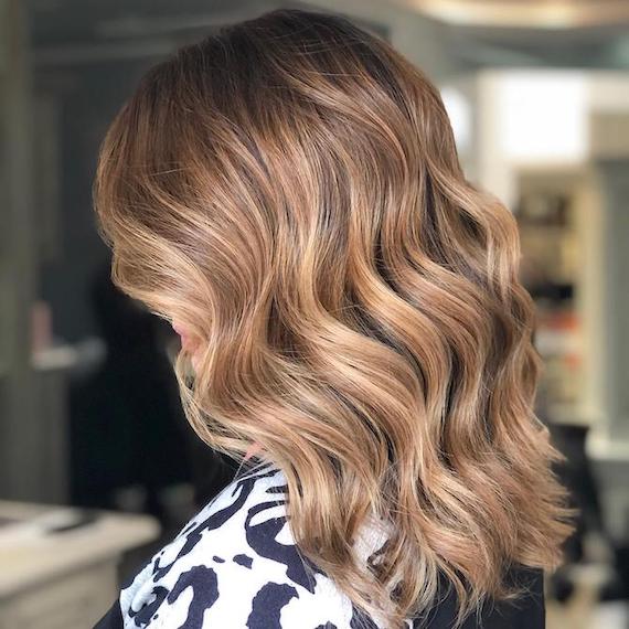Back of woman’s head with mid-length, medium blonde, wavy hair, created using Wella Professionals.