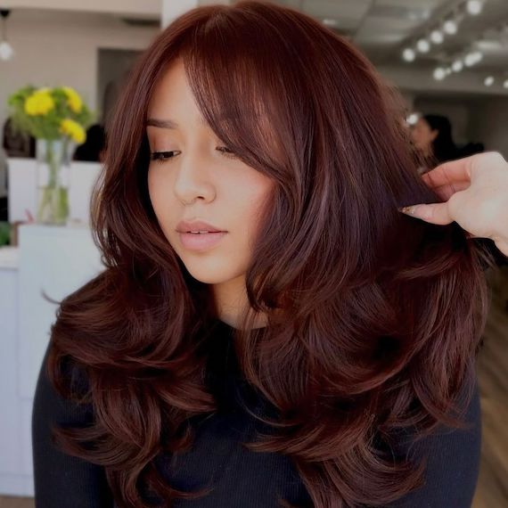 Model with long, cherry chocolate hair styled in a bouncy blow dry.
