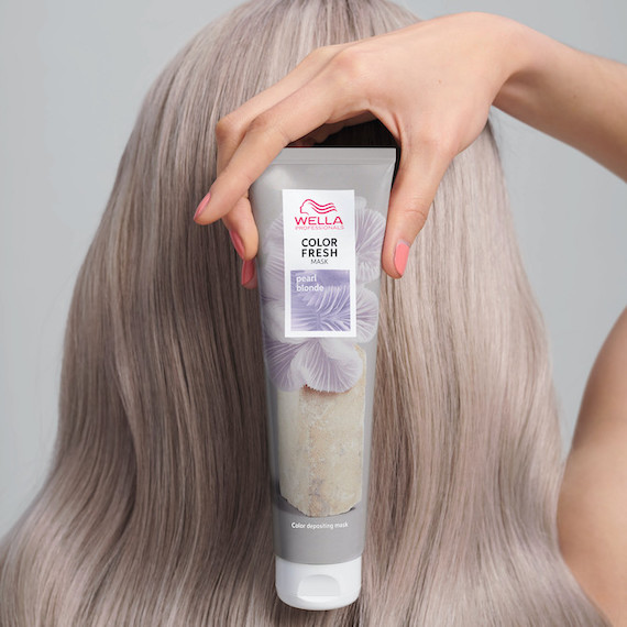 Back of woman’s head with blonde hair. She’s holding up with Color Fresh Mask in Pearl Blonde.