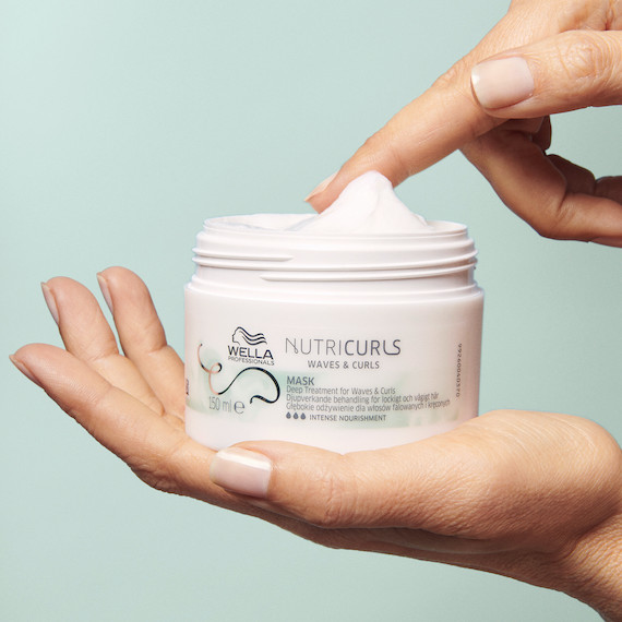 Model holds open jar of NutriCurls Mask.