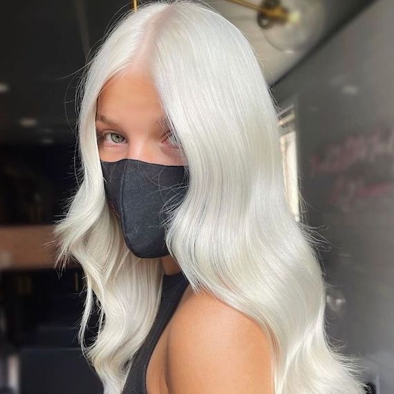 Model with long, wavy, nordic white hair faces camera.