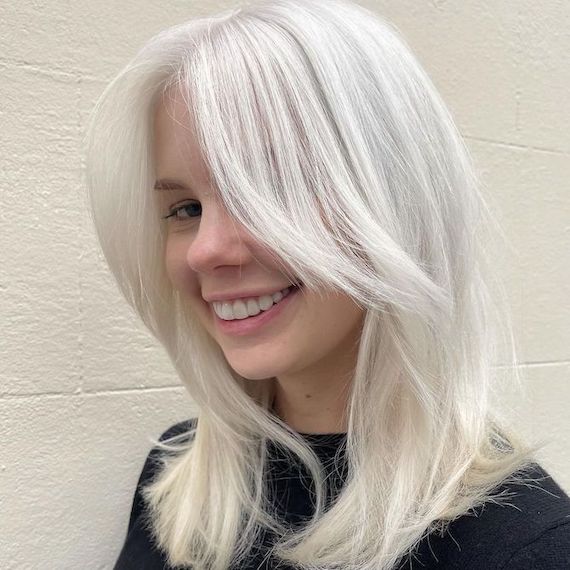 Model with nordic blonde hair smiles at the camera.