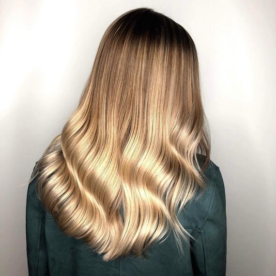 Back of woman’s head with full, blonde balayage, created using Wella Professionals.