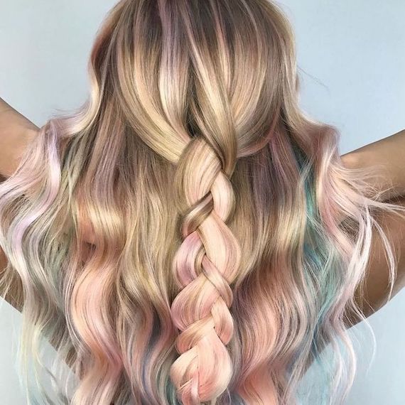 Back of model’s head with long, golden blonde hair and pastel rainbow balayage through a braid.