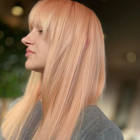 Model with long, straight, platinum blonde hair with a subtle peach glow.
