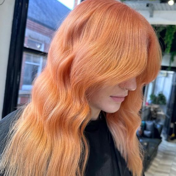 Model with long, peach blonde hair styled in beachy waves.