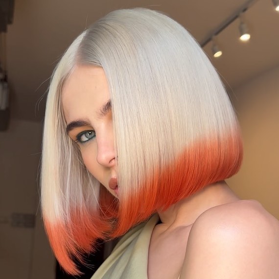 Model with platinum blonde bob haircut featuring an acid peach dip-dye.