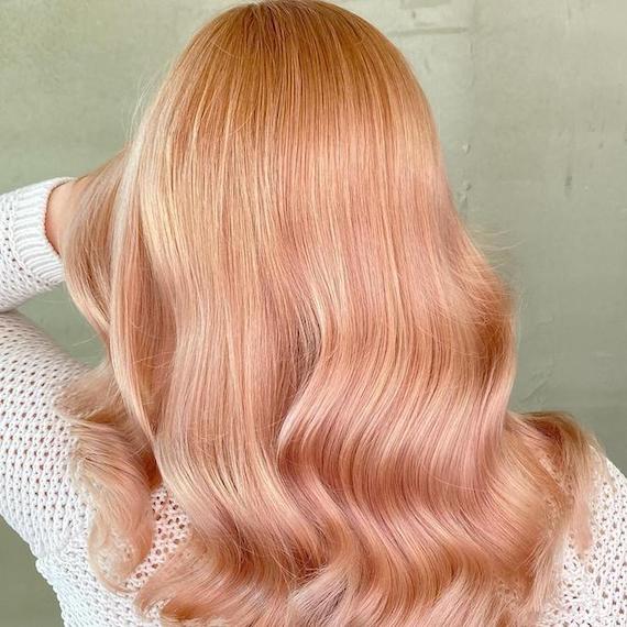 Hinterkopf einer Frau mit gewelltem, roségoldenem Haar, kreiert mit Wella Professionals.