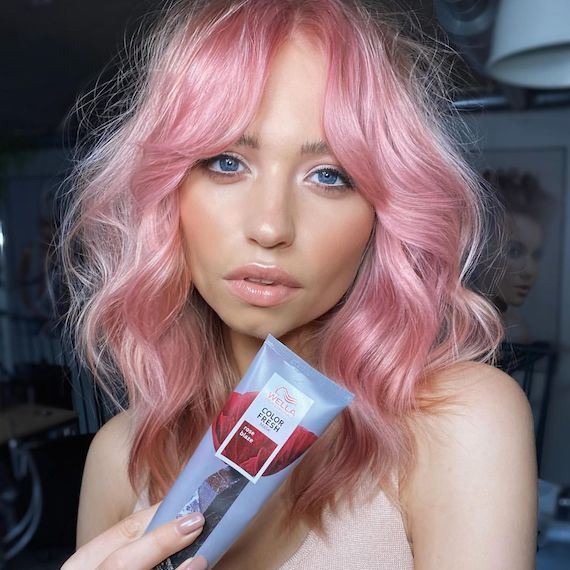 Model with wavy, candy pink hair holds up Color Fresh Mask in Rose Blaze.